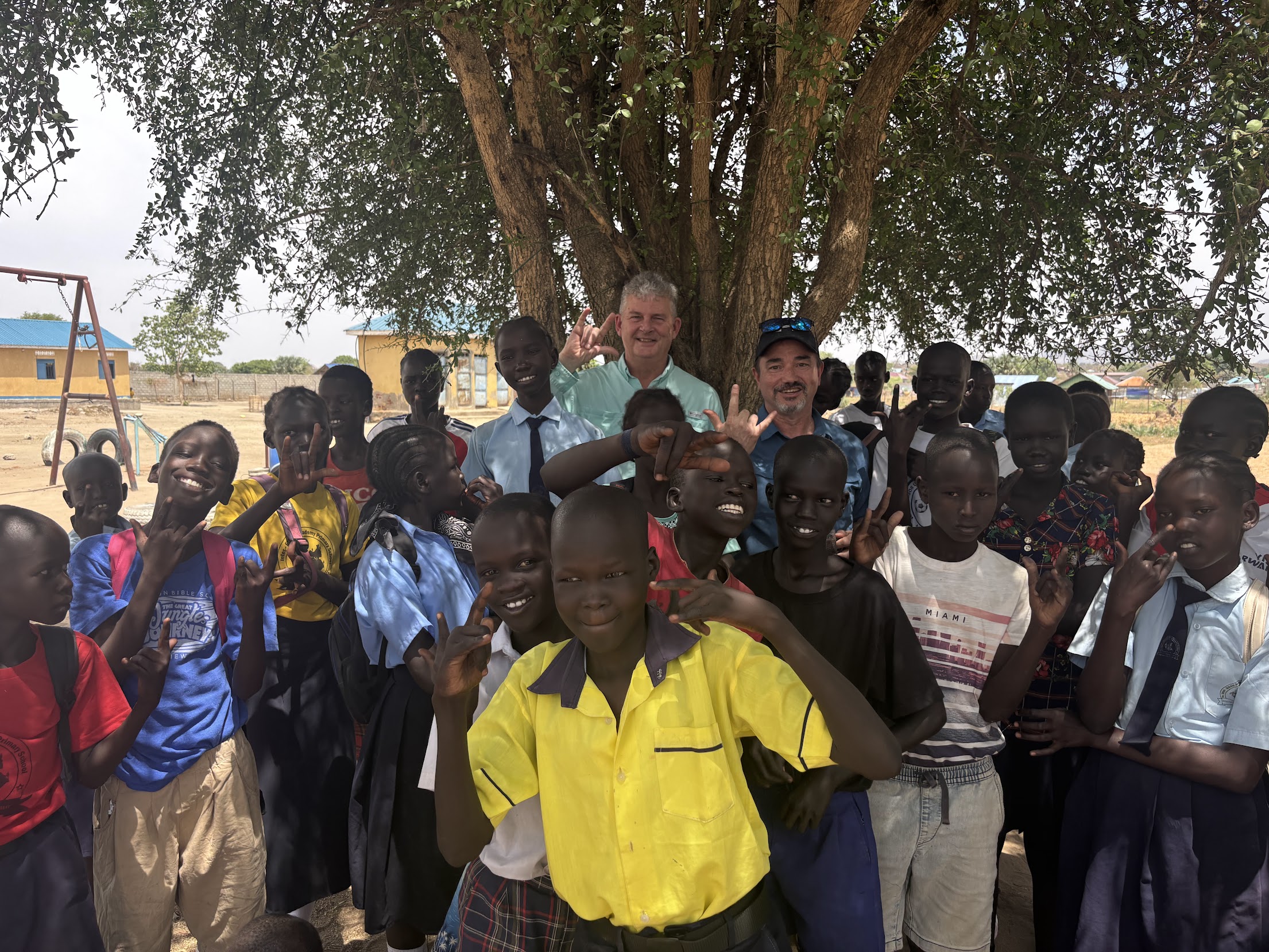 Children waving and smiling at a Nile Orphan Care community program